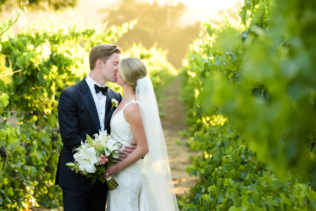 Bride kiss between grape vines at one of the Top 10 Wedding Venues in Sonoma.