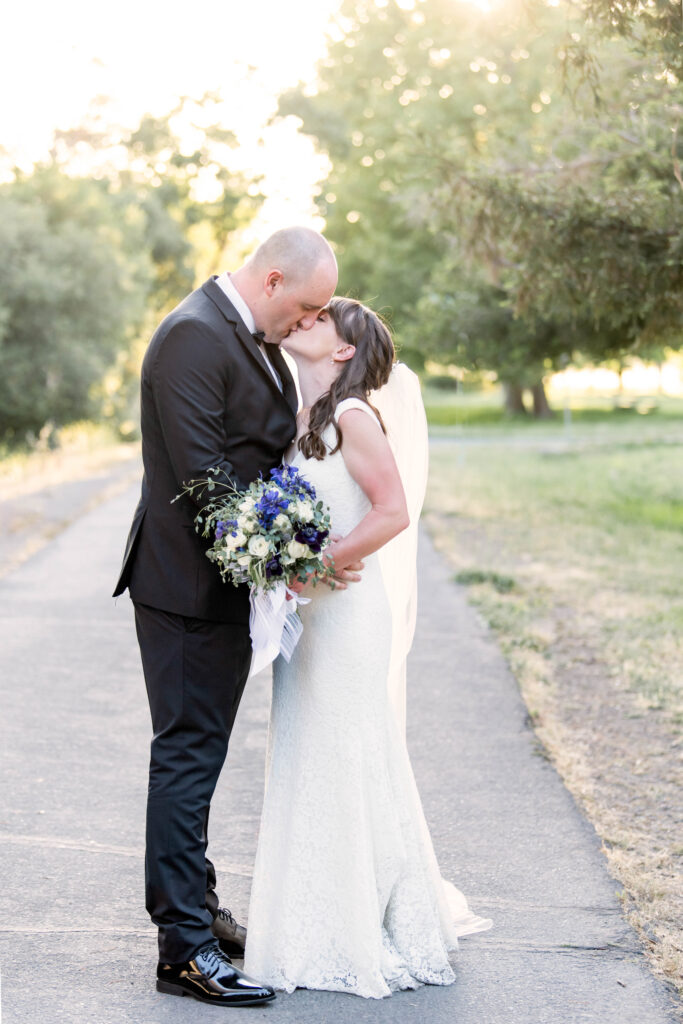 Beautiful bride and groom kiss in golden-hour light in California. 