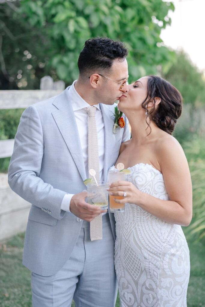 Bride and groom kiss while holding cocktails after wedding at Vine Hill House in Sebastopol.