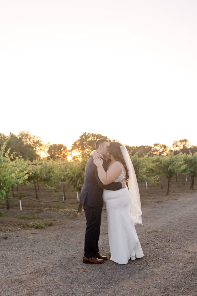 Romantic sunset kiss between bride and groom at deLorimier Winery Wedding Venue in Sonoma County.