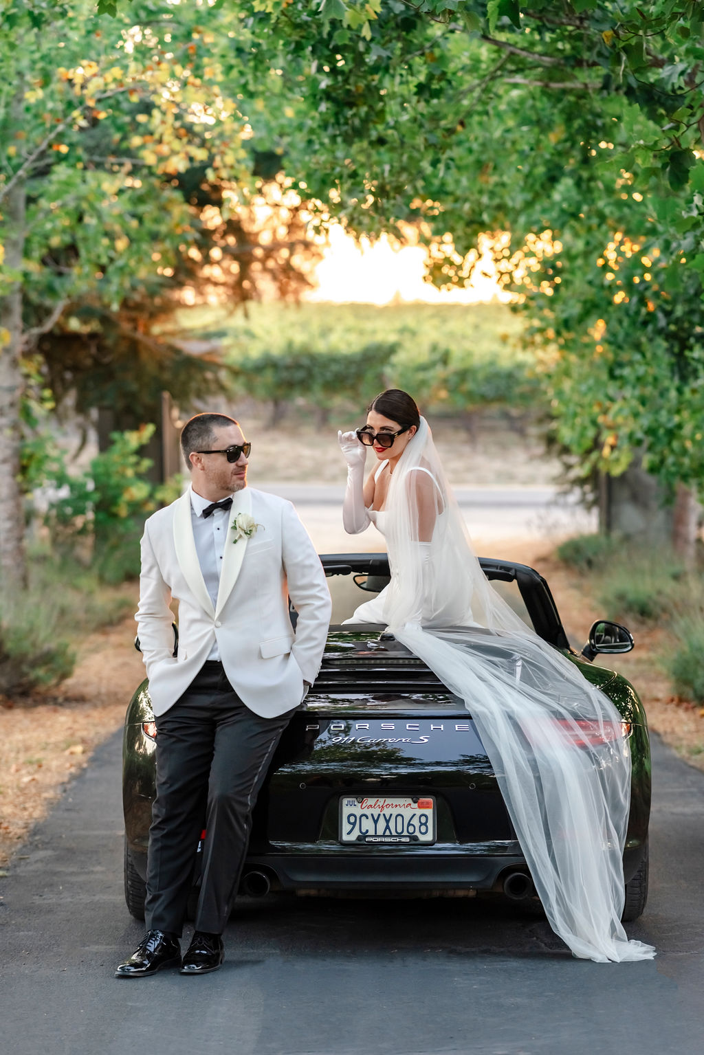How to have a Vine Hill House wedding in Sonoma. Damo and Sorcha on a car framed by the vineyard vines.