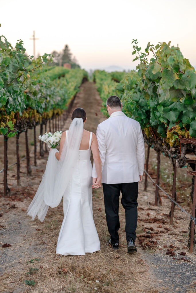 Sonoma Vine Hill House Wedding, couple holding hands walking through vineyard. 