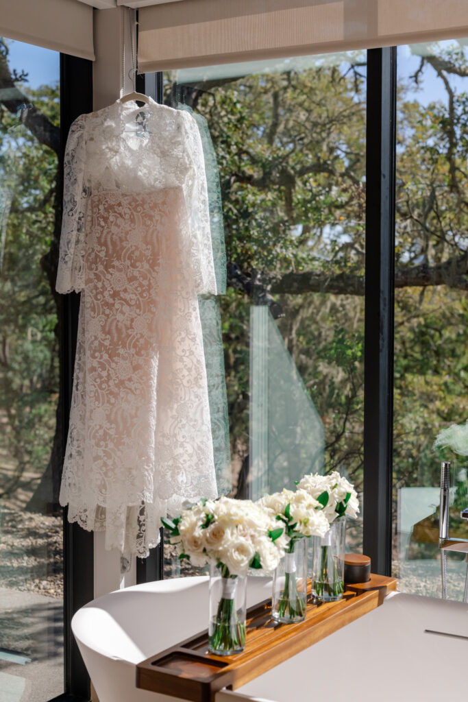 Wedding detail photos in bathroom with flowers and dress.