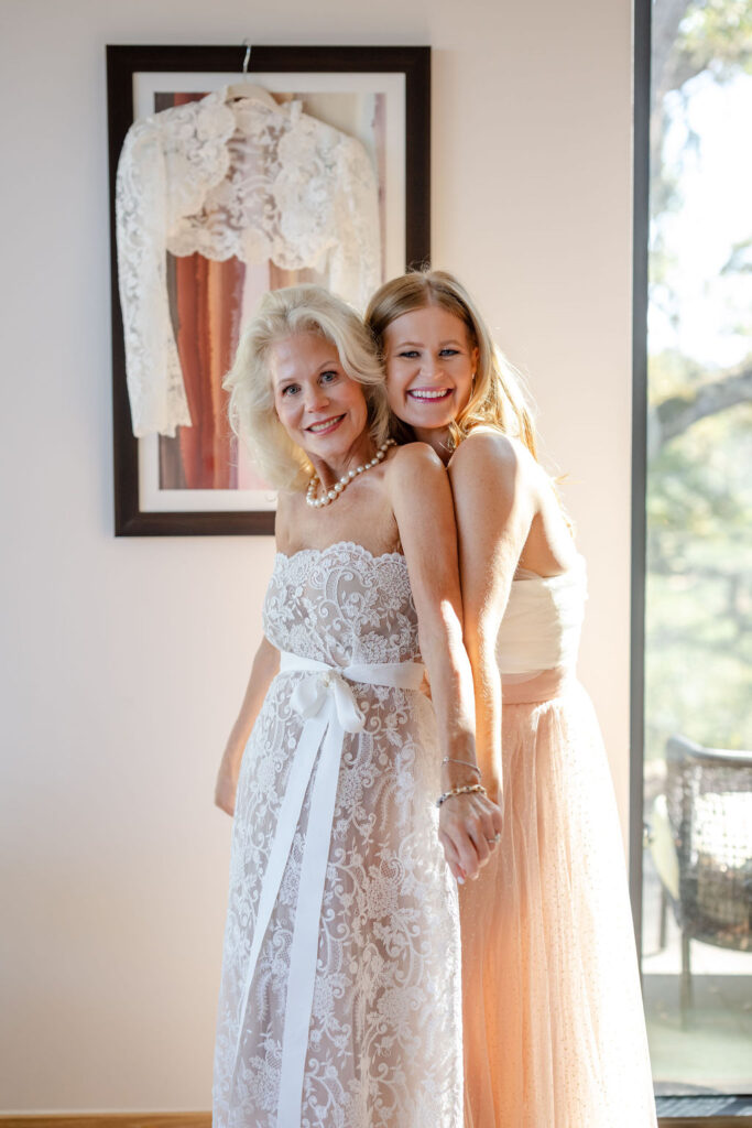 Bride and her mother smiling together in a sunlit suite at Montage Healdsburg, wearing lace wedding dress before the ceremony