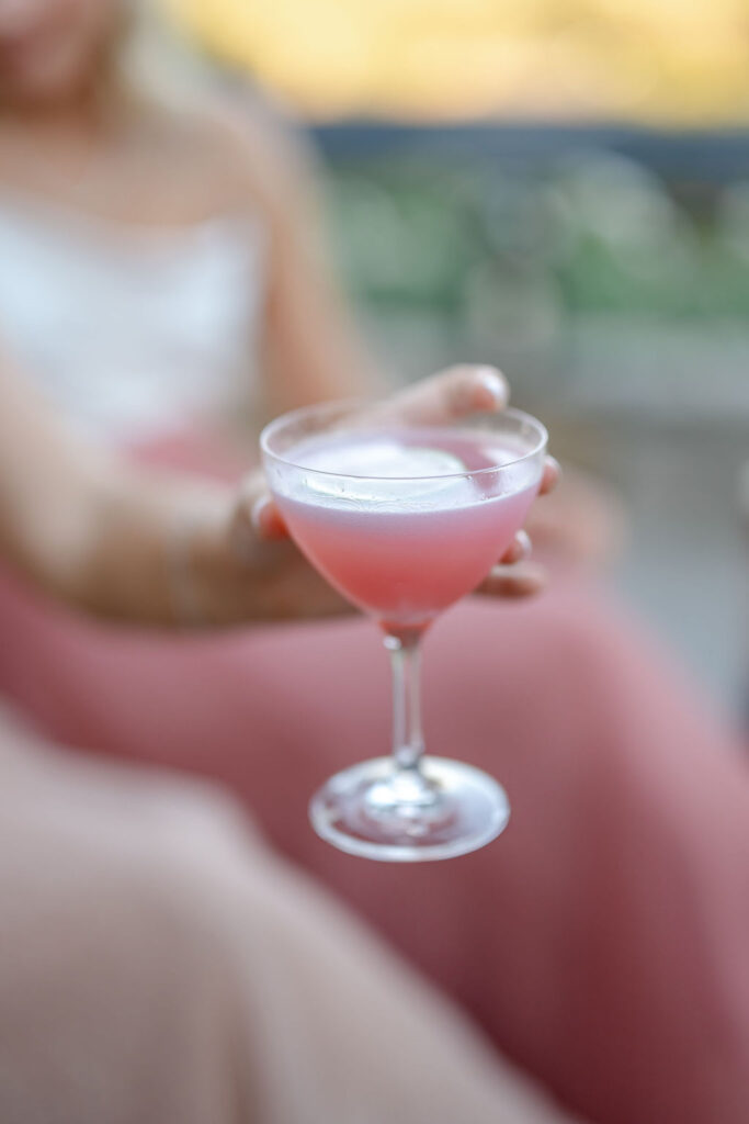 Close up of a pink cocktail in a coupe glass held by a wedding guest during the reception at Montage Healdsburg.