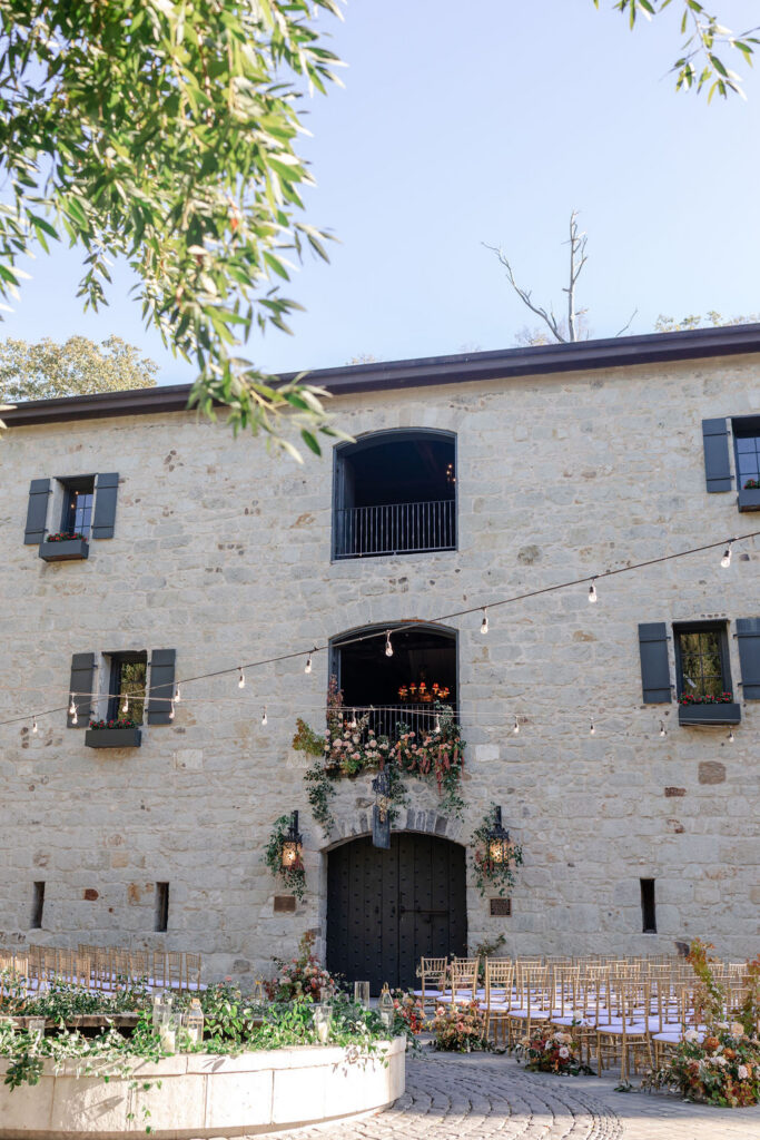 Historic stone courtyard ceremony space at Buena Vista Winery in Sonoma set with gold chairs and floral arrangements for a wine country wedding.