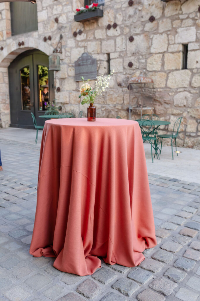 Cocktail table with terracotta linen set in the stone courtyard at Buena Vista Winery wedding venue in Sonoma.