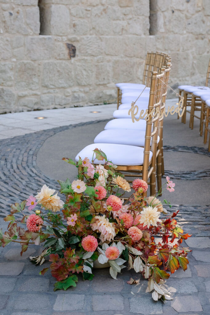 Colorful floral aisle arrangement beside ceremony chairs in the courtyard at Buena Vista Winery wedding venue in Sonoma.