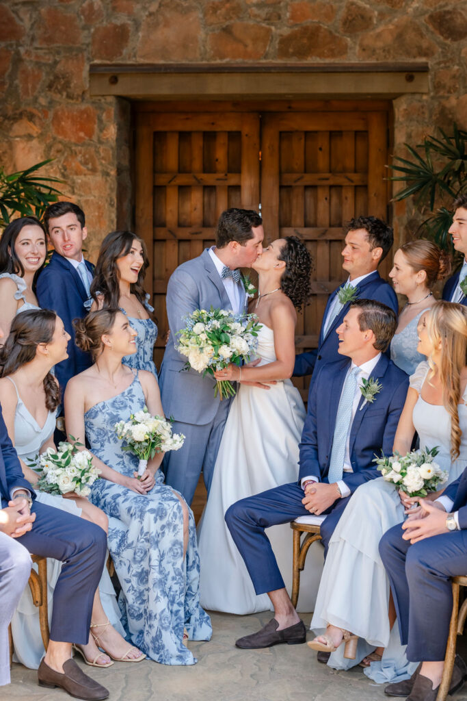 Bride and groom kissing surrounded by wedding party at Mayacama Golf Club wedding venue in Sonoma.
