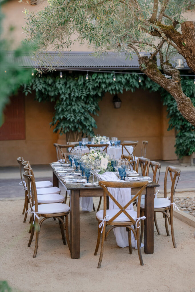 Long wooden reception tables under olive trees at Mayacama Golf Club wedding in Sonoma