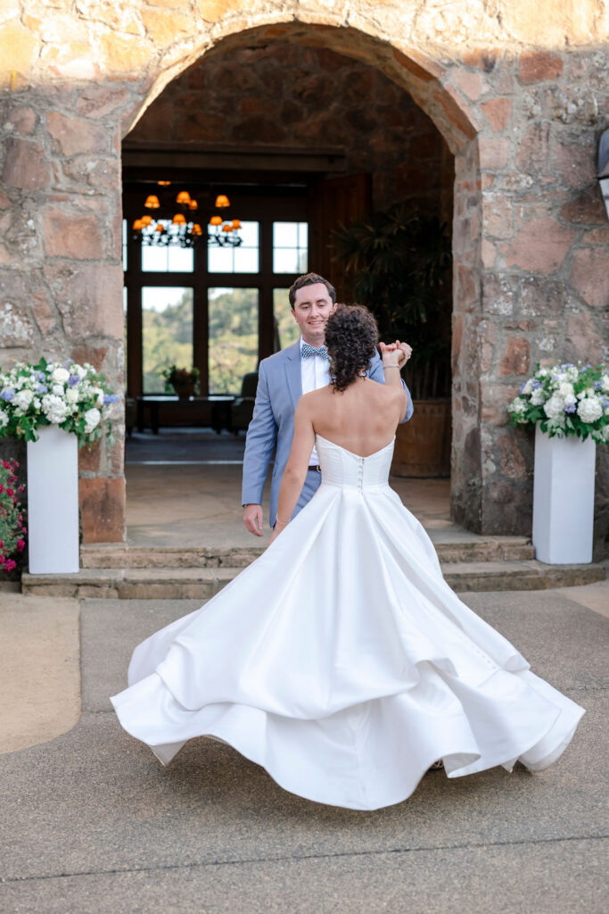 Bride twirling in front of stone archway at Mayacama Golf Club wedding venue in Sonoma.
