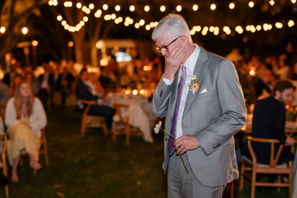 Father of the bride overcome with emotion holding a flower at Healdsburg wedding reception, photographed by Alicia Parks Photography